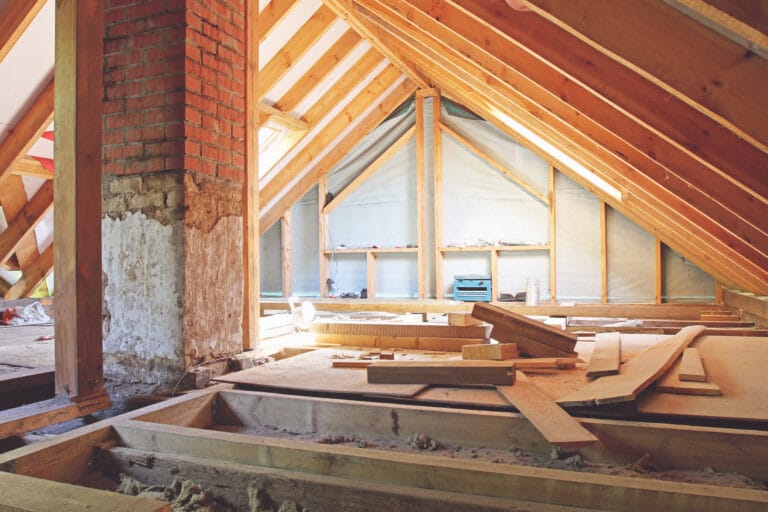 Unfinished attic with wooden beams and bricks.